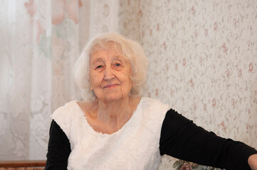 The portrait of a cheerful smiling senior woman over home background