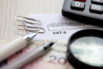 Declaration for tax on goods and services VAT-8 form on accountant table with pen and polish zloty...
