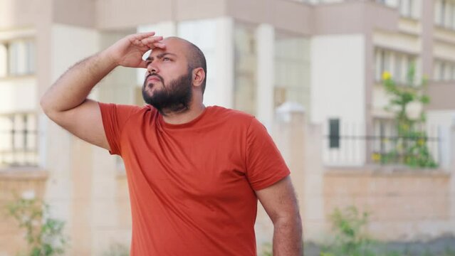 Bald indian Man Looking Around With Hand On Forehead