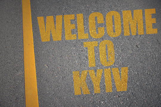 asphalt road with text welcome to Kyiv near yellow line.