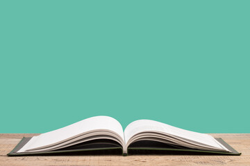 open book. Composition with hardback books, fanned pages on wooden deck table and green background. Books stacking. Back to school. Copy Space. Education background.