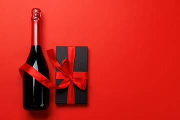 Champagne and gift: Celebratory duo on a red background with text space