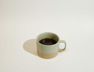 A pastel green coffee cup against the white background. Minimal concept of coffee culture. Copy space. 