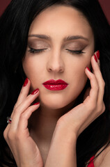 Fototapeta premium Beauty studio portrait of young beautiful woman with closed eyes against red background.