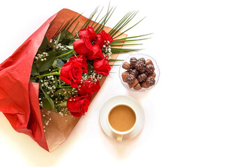 Top view photo of bouquet of red roses, a cup of coffee, chocolate candies isolated on white background with copyspace. Festive concept. Happy mother's day, Happy Valentine's Day, Happy Birthday card.