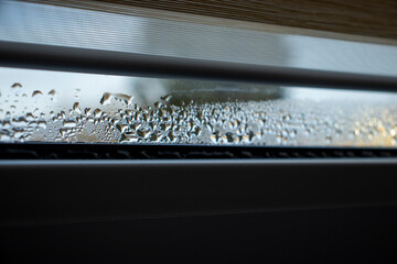 Indoor close-up of a leaky window with steam and condensate background