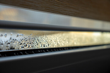 Indoor close-up of a leaky window with steam and condensate background