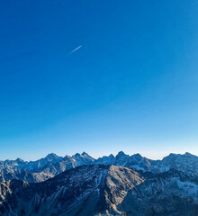 Samolot na tle pasma górskiego w bezchmurną pogodę z widoku najwyższego szczytu w Polsce, Kozi Wierch  © Patryk