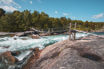 Fototapeta na wymiar Abenteuerliche Hängebrücke über Wildwasserfluss