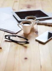 Black coffee with blank digital tablet and mobile phone, magazines and glasses on the table