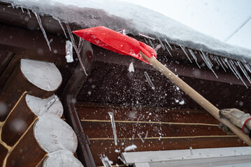 Shovel for snow removal, Icicles on the roof, snow removal in January and February. Working outside in winter.