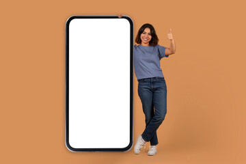 Positive arab woman stand by big phone with blank screen