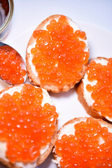 Red salmon caviar on bread and butter. A sandwich with caviar and butter on a plate.