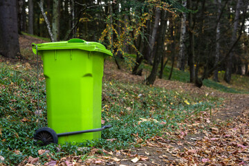 Big green trash can in the forest, concept of environmental protection