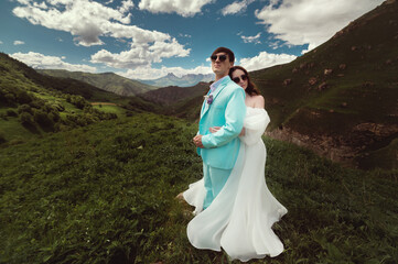 Beautiful wedding photo in the mountains, a wedding couple of newlyweds in love hugging against the backdrop of greenery and a cloudy sky