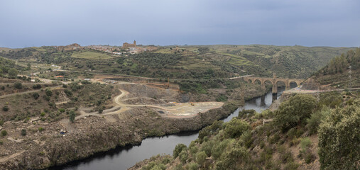 Panoramic photograph of the town of Alcántara and its bridge over the Tagus River. An authentic work of engineering carried out by the Roman Empire. Alcantara, Caceres, Spain - obrazy, fototapety, plakaty