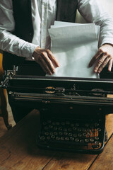 A writer putting blank pages into a typewriter - 717059973