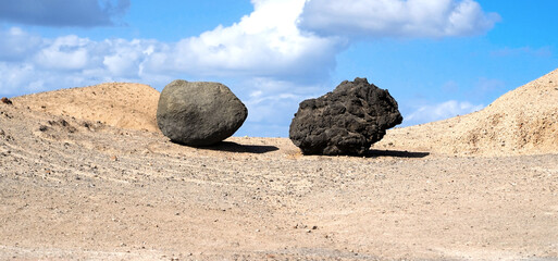 A creative photo with two volcanic formations, dark stones on a white sand landscape.