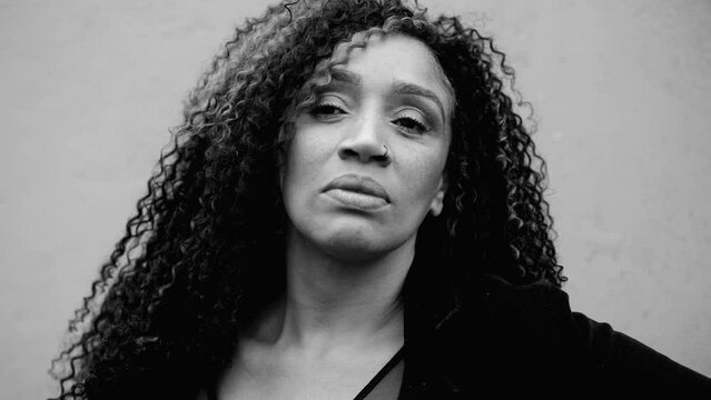 Portrait of a serious South American black woman looking at camera with stern solemn expression in monochromatic, black and white. Intense close-up face