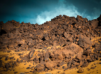 Volcanic landscape with basalt rocks, stones and sand, a volcano terrain at sunset.