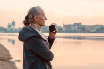 A woman, lady drinks a coffee and enjoys the sunset.