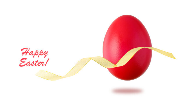 Painted in red natural easter chicken egg with golden gift ribbon flying isolated on white background. Happy Easter spring decoration.