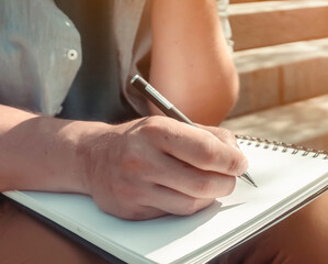 Man is writing notes on a white paper, hands closeup.