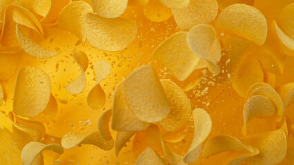 Freeze motion of flying fried potatoes chips on yellow background