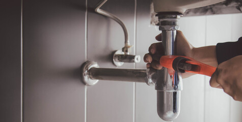 plumber at work in a bathroom, plumbing repair service , fix water plumbing leaks, replace the kitchen sink drain - obrazy, fototapety, plakaty