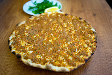 Freshly Baked Lahmacun on a Wooden Table, a Traditional Turkish Pizza Topped with Minced Meat and Herbs