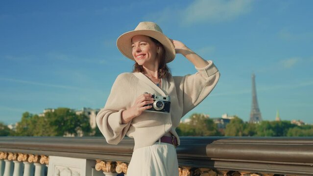 Attractive tourist with camera on bridge overlooking Eiffel Tower