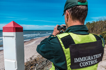 Immigration control officer surveying the coast with binoculars, vigilant in national border protection duties on a sunny day