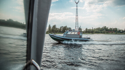 Dynamic shot of a military speed boat in action on the water with spray and a cloudy sky backdrop