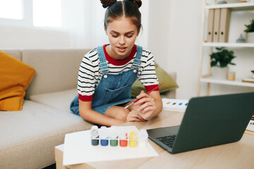 Happy Teenage Girl Doing Homework, Painting and Creating Art on Laptop in Modern Indoor Studio