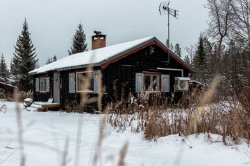 Schwarzes schwedisches Waldhaus im Winter bei Schneefall