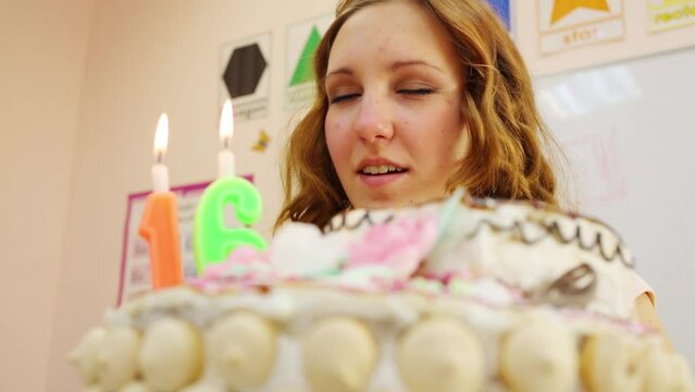 Girl teenager blows out candles 16 on cake at birthday