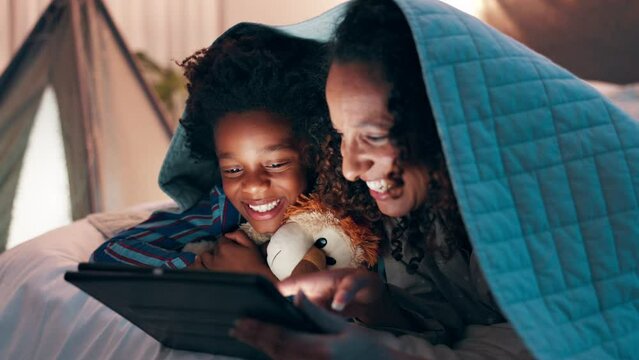 Tablet, night and mother and son on a bed with cartoon, movie or streaming funny video in their home. Digital, app and mom with kid in a bedroom for online comic, love and bonding with blanket fort