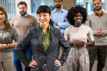 Asian boss standing in front of her colleagues in the office