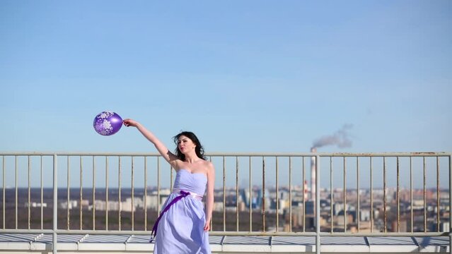 Woman with purple balloon standing on roof, lifting balloon up