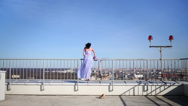 Woman climbing fence on roof with ball, picking it up 