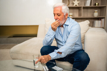 Middle aged senior man with medical pill and glass of water. Mature old senior grandfather taking medication cure pills vitamin. Age prescription medicine healthcare therapy concept