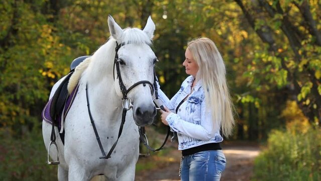 Woman in nature with white hair stroking white horse