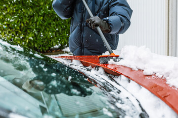 Cleaning snow from windshield. Cleaning and clearing the car from snow on a winter day.