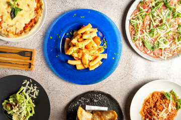 Top down view of a delectable spread of Italian dishes on a table pizza, pasta, carpaccio, and...