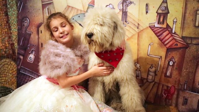Little girl in evening dress and fur mantle sits with sagged dog
