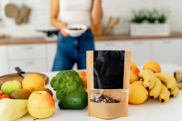Woman Standing in Kitchen Next to Counter Filled With Fruits and Vegetables. A photo of a woman standing in a kitchen next to a counter filled with an abundance of fresh fruits and vegetables.