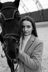 Obraz premium Woman Standing Next to a Horse at a Ranch. A woman stands beside a horse at a ranch, creating a connection through their shared presence.