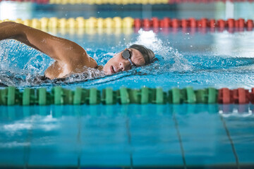 Elite female athlete, professional swimmer during a front crawl swimming workout. Concept of hard training for a competition.