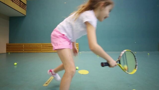Back of girl in shorts learning to beat off balls from wall