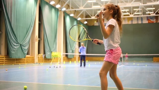 Funny girl learns to hold racket and beat off balls. 